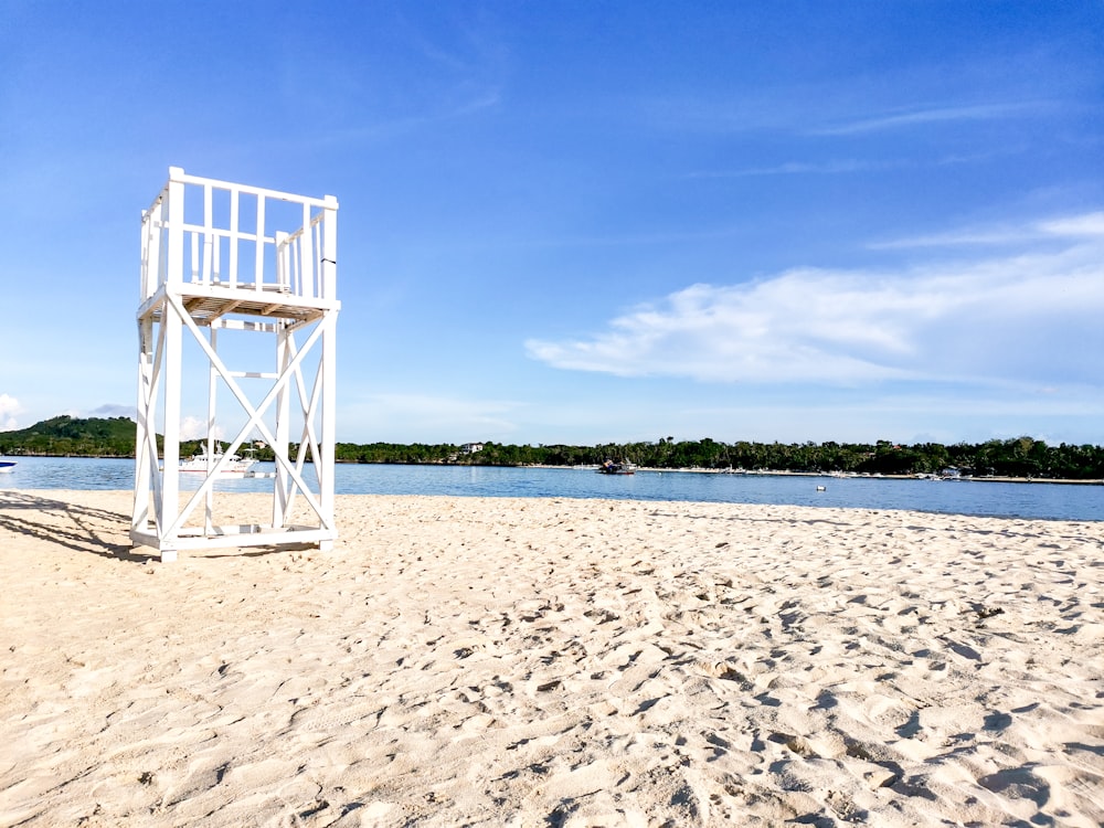 a lifeguard tower on a sandy beach next to a body of water