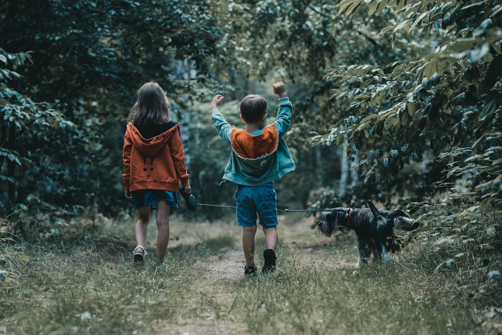 a couple of kids that are walking a dog