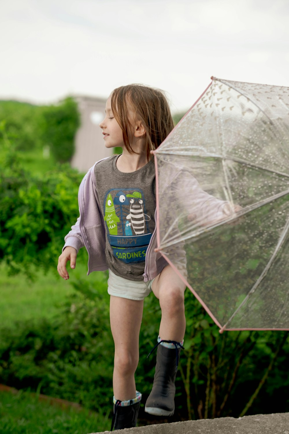 a little girl holding a clear umbrella in her hand