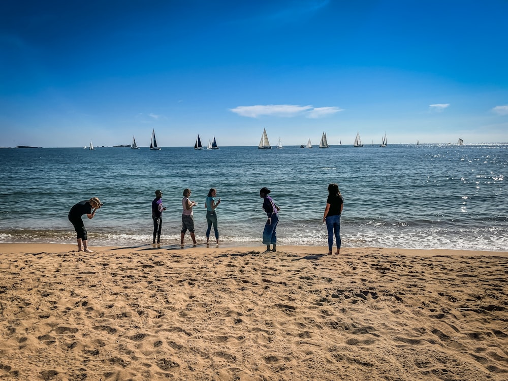 a group of people standing on top of a sandy beach