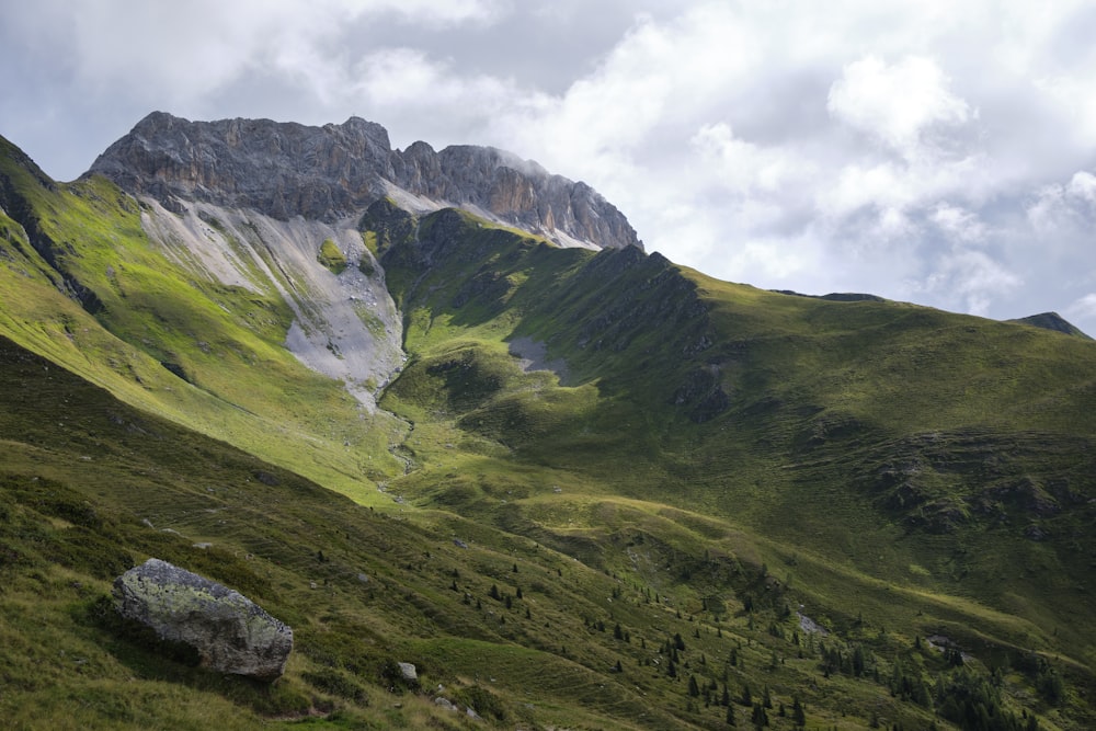 a mountain range with a large rock in the foreground