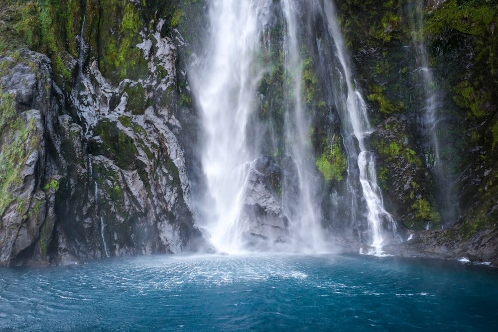 a large waterfall with a body of water in front of it