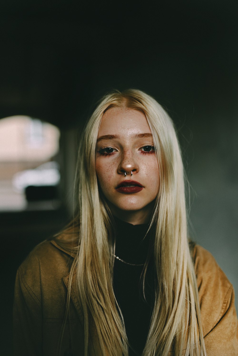 a woman with long blonde hair wearing a brown jacket