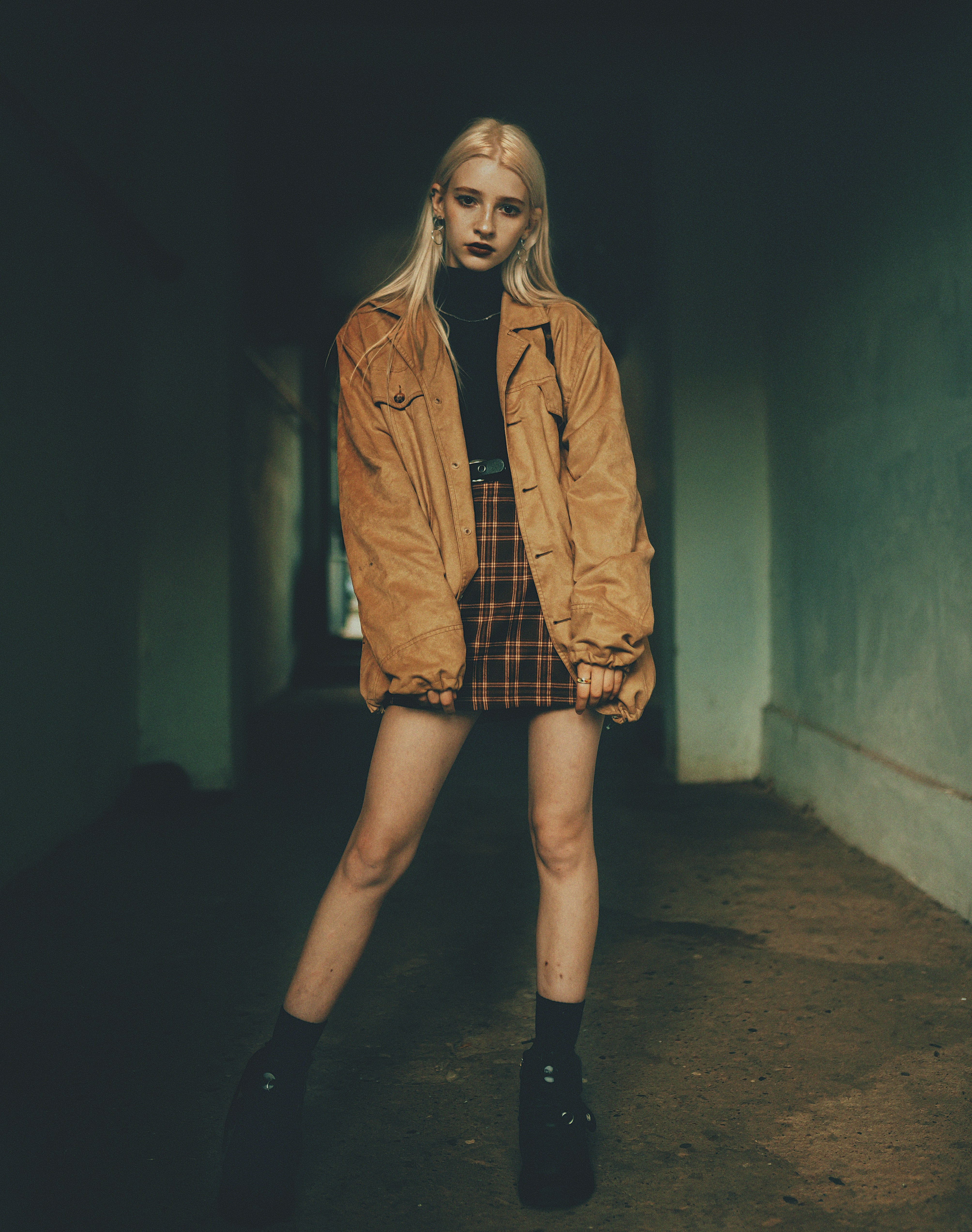 a woman in a brown jacket and plaid skirt