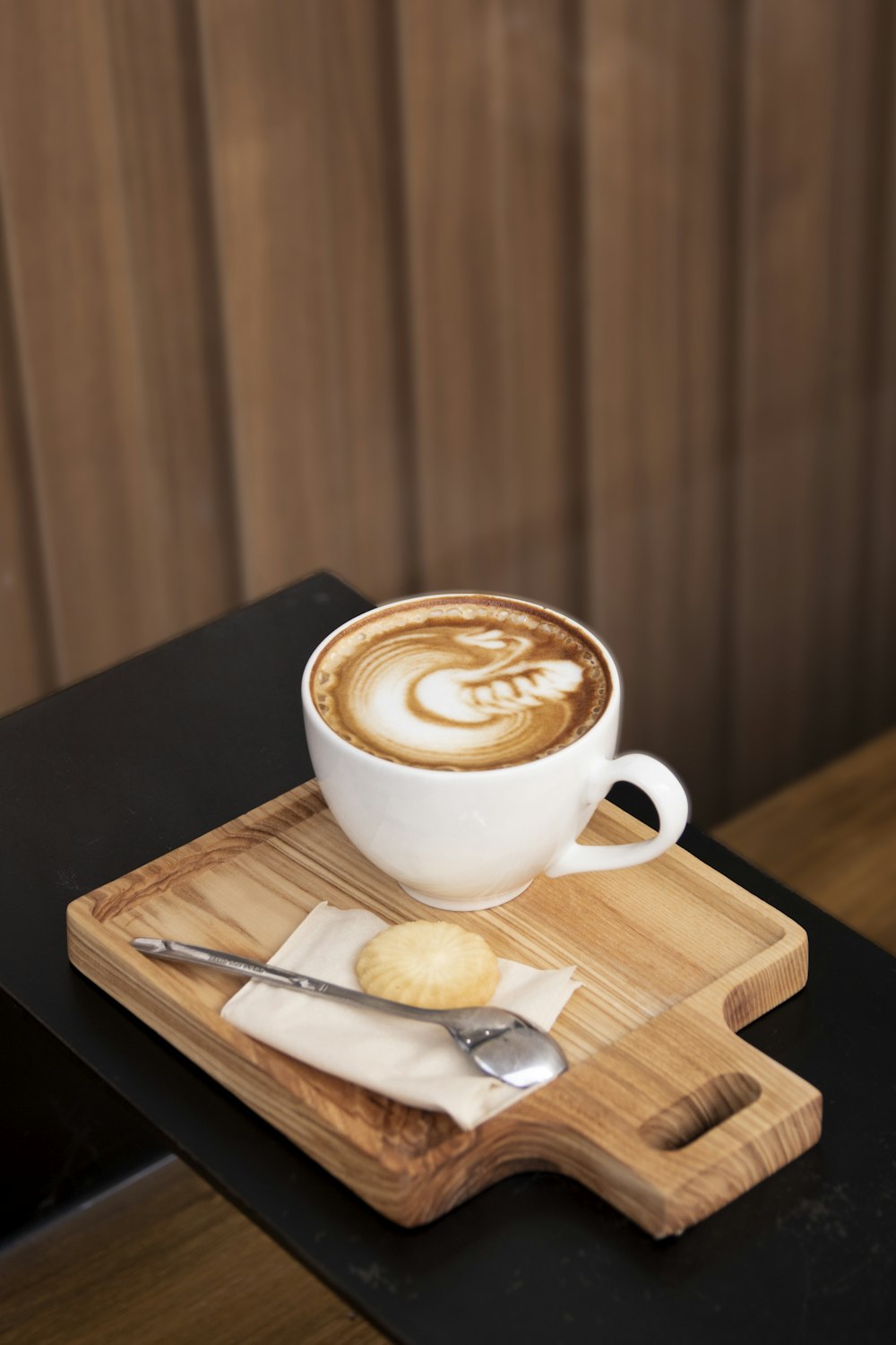 a cup of cappuccino on a wooden tray