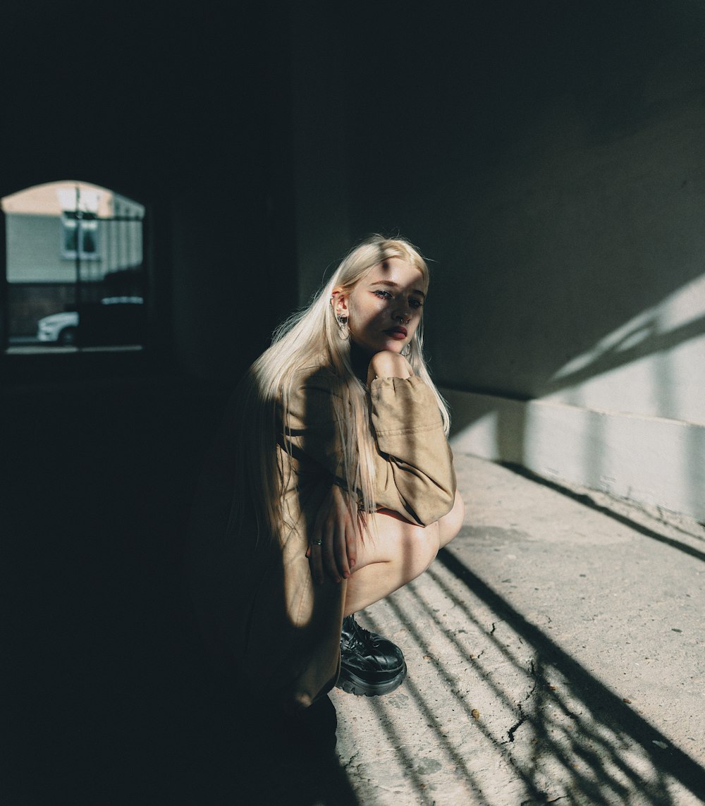 a woman sitting on the ground next to a wall