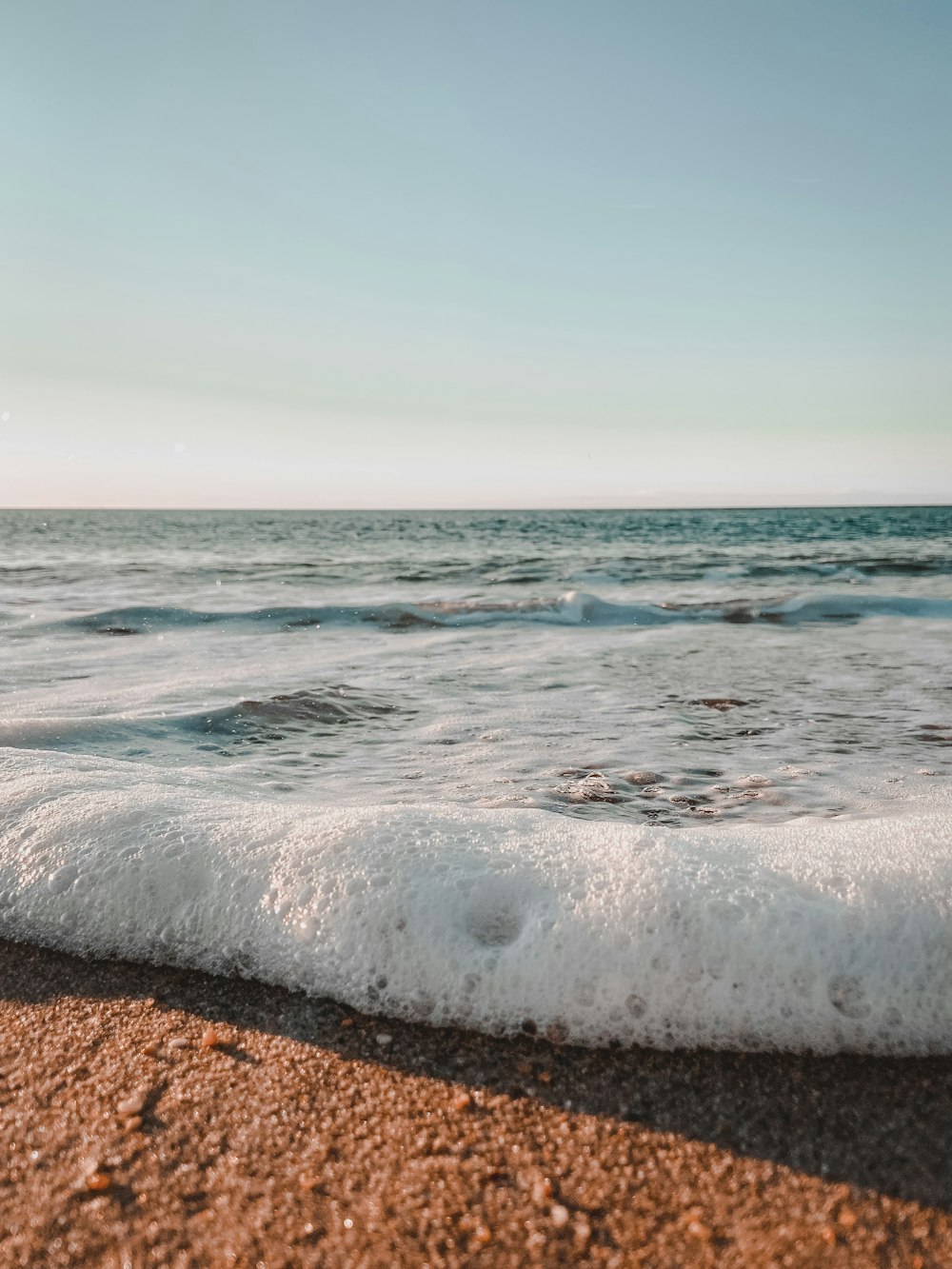 a wave is coming in to the shore of a beach