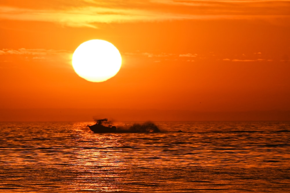 um barco na água ao pôr do sol com o sol no fundo