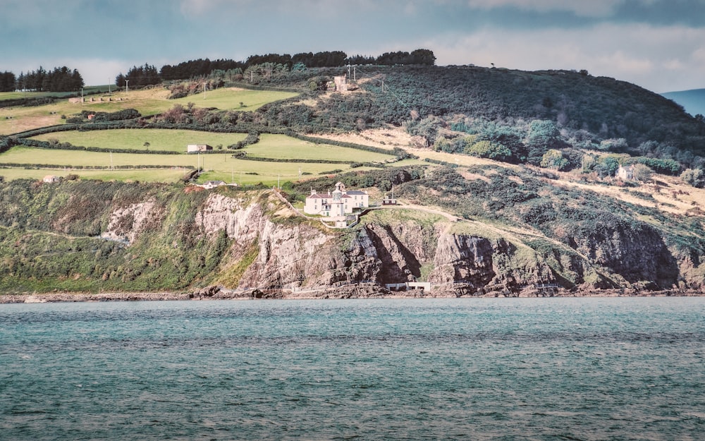 Un grande specchio d'acqua seduto sotto una collina verde lussureggiante