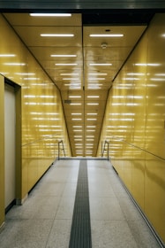a long hallway with yellow walls and a metal hand rail