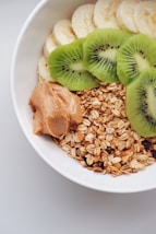 a bowl filled with oats, kiwi, and peanut butter