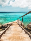 a wooden walkway leading to the ocean on a cloudy day