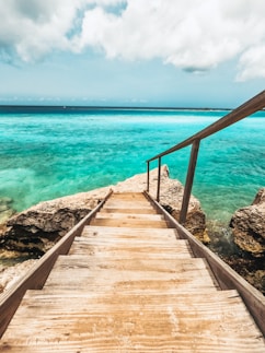 a wooden walkway leading to the ocean on a cloudy day