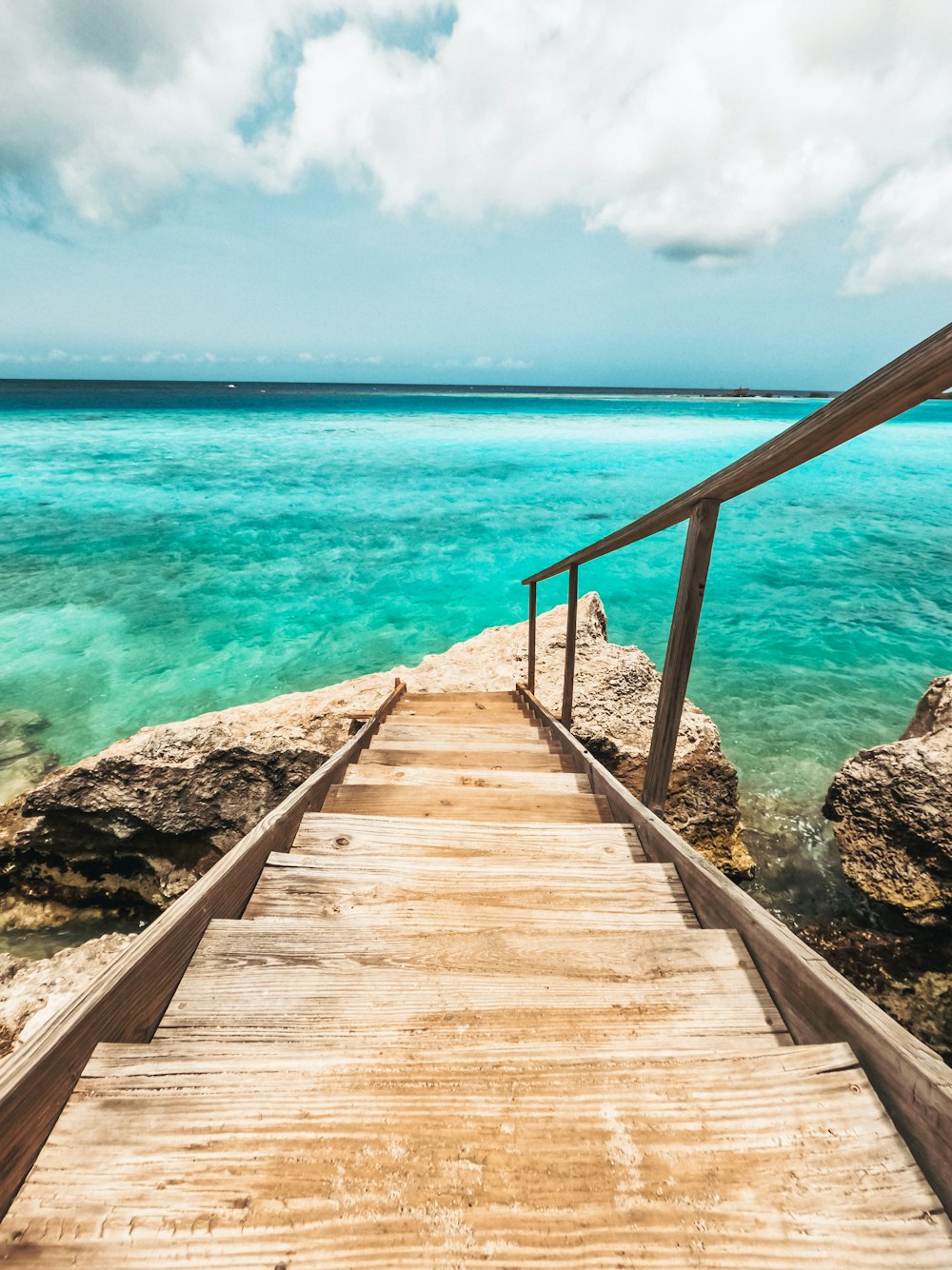 a wooden walkway leading to the ocean on a cloudy day