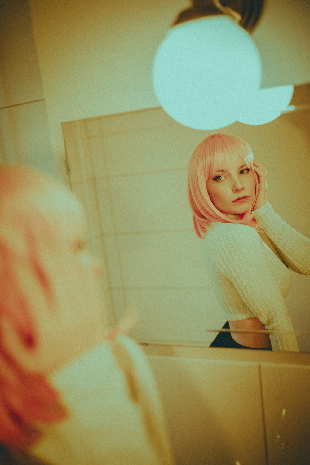 a woman with pink hair standing in front of a mirror