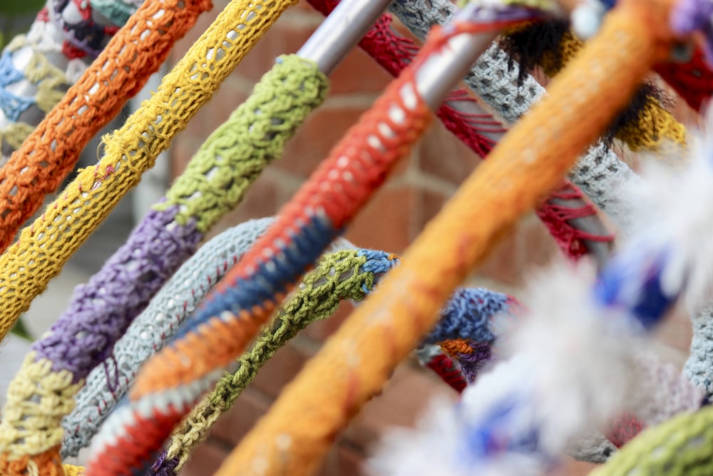 a bunch of colorful ropes hanging from a brick wall