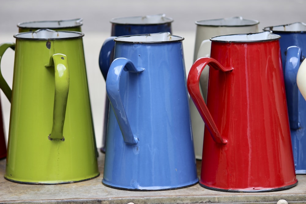 a row of colorful coffee mugs sitting on top of a shelf