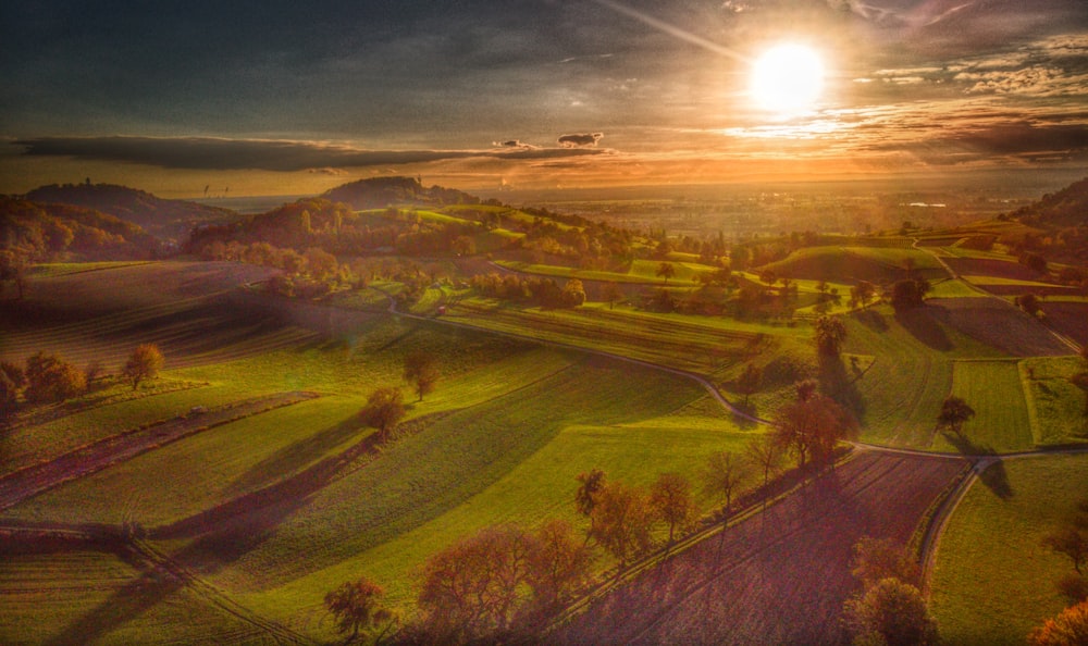 the sun is setting over a green field