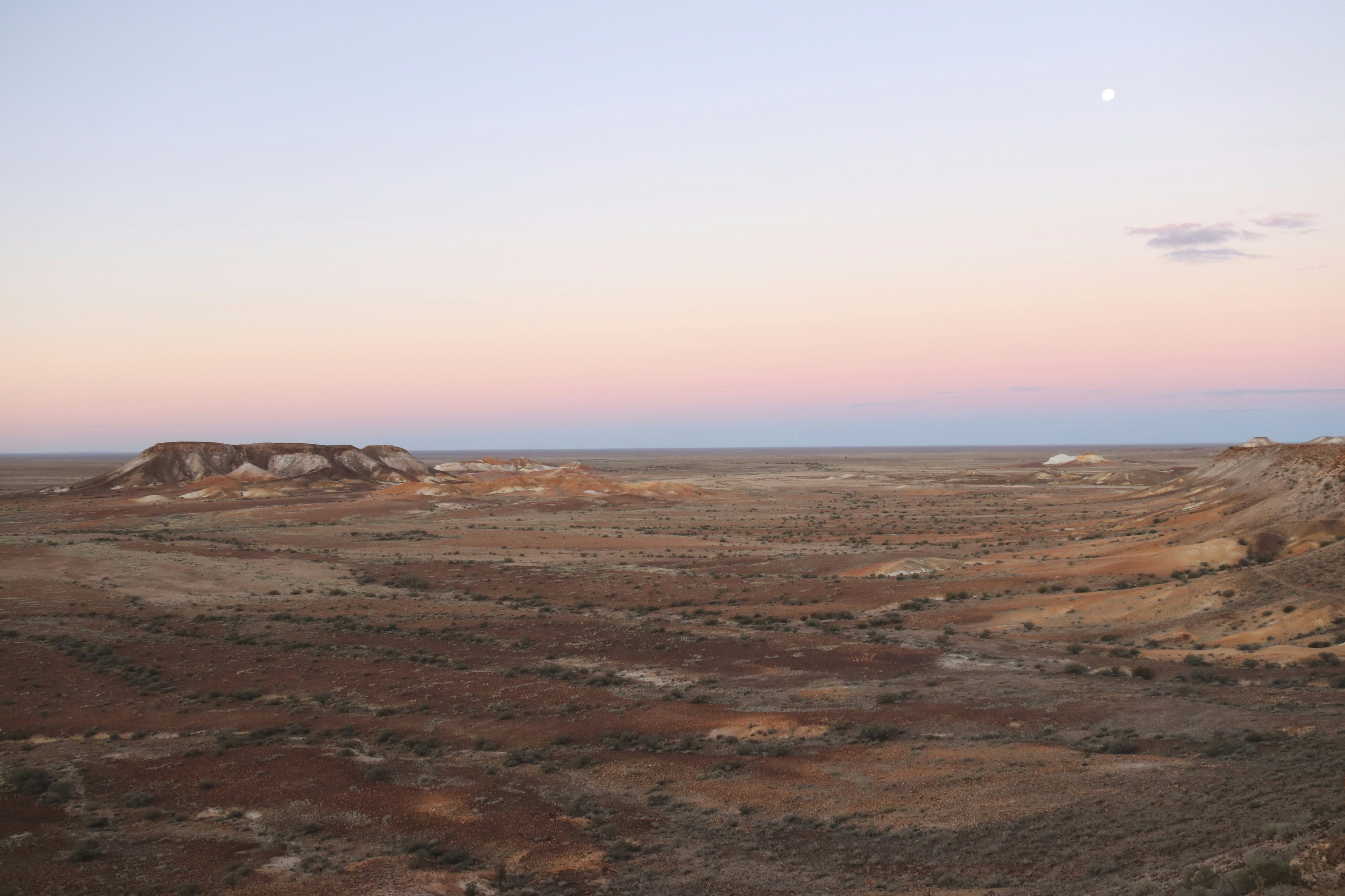 a desert landscape with a moon in the sky