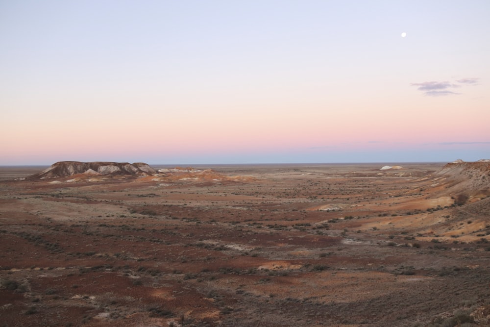 a desert landscape with a moon in the sky