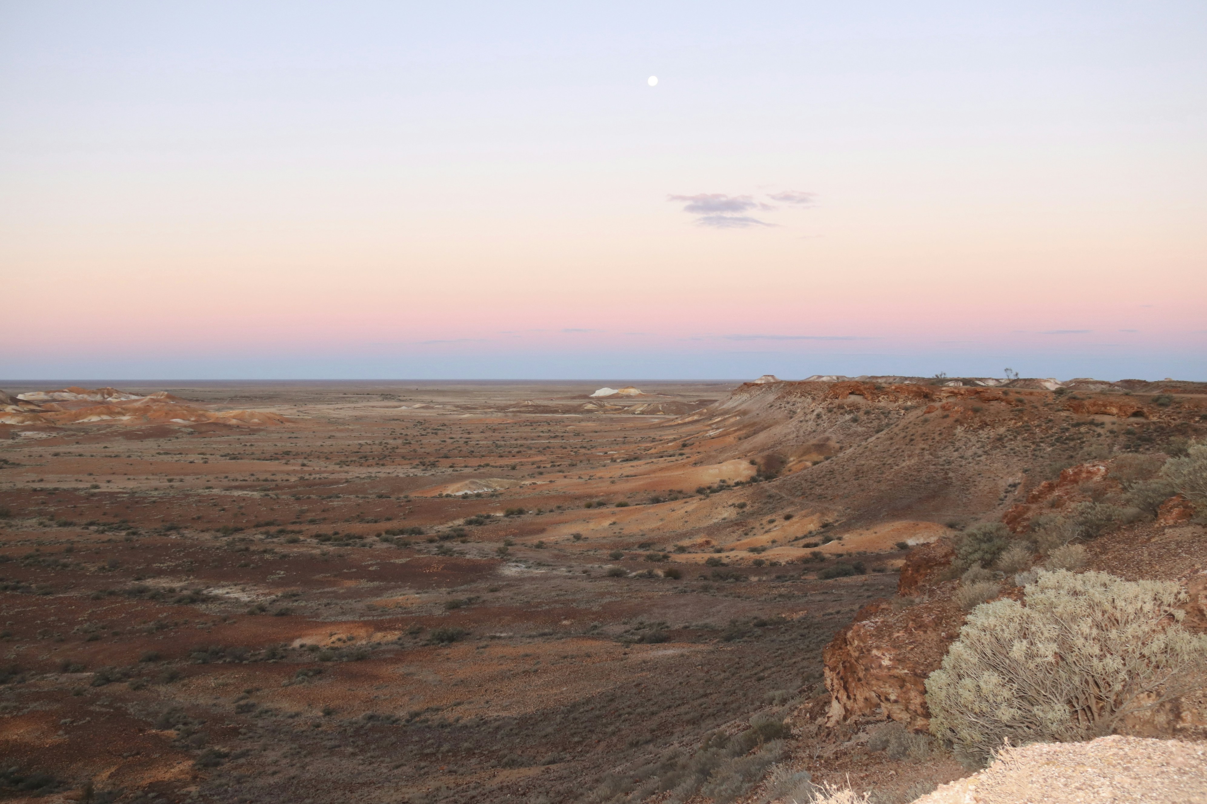 a view of a desert with a moon in the sky