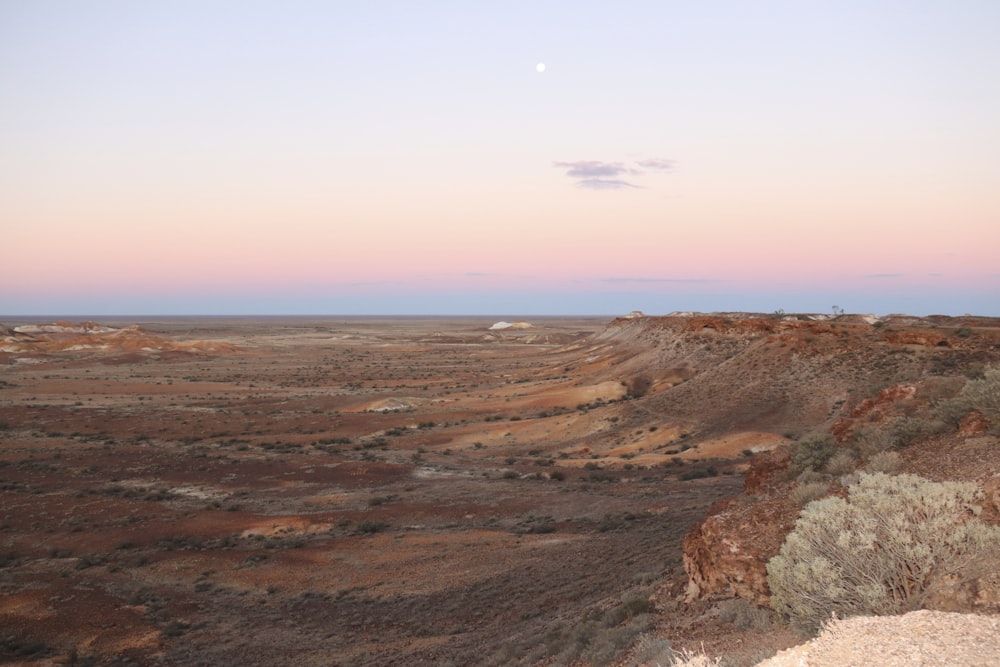 a view of a desert with a moon in the sky