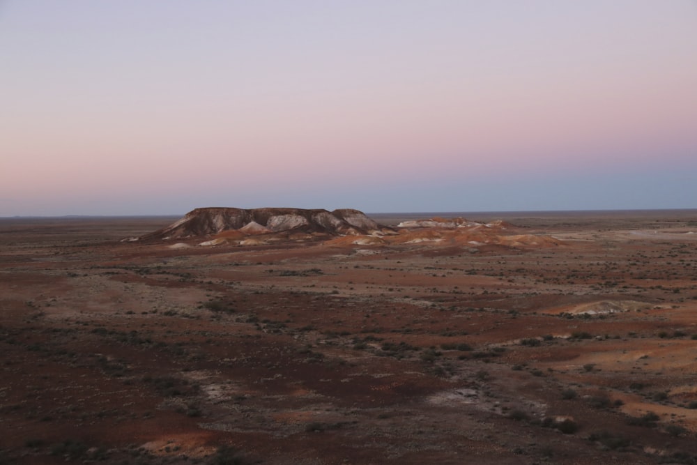 a desert landscape with a hill in the distance