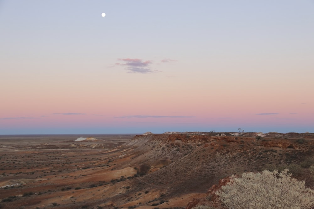 the moon is setting over a desert landscape