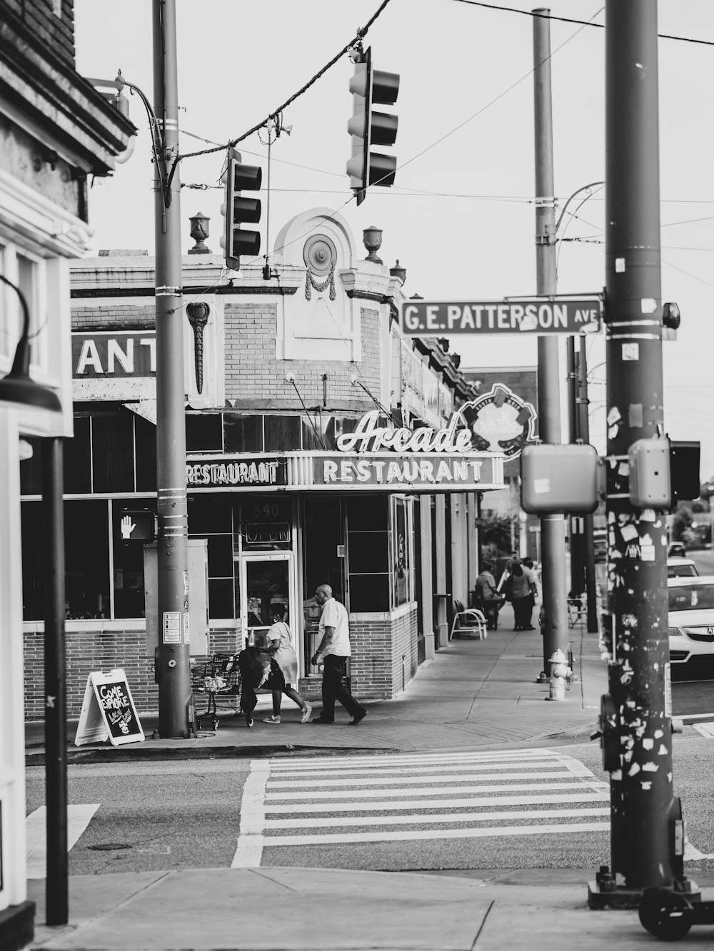 a black and white photo of people crossing the street