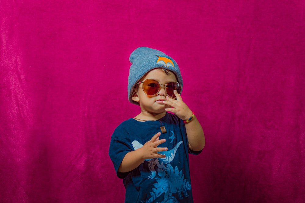 a little boy wearing sunglasses and a hat