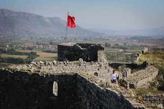 a man sitting on a stone wall next to a flag