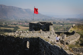a man sitting on a stone wall next to a flag