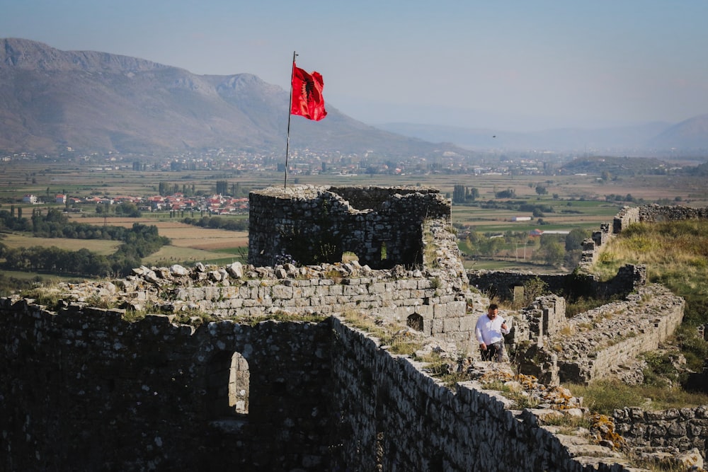 a man sitting on a stone wall next to a flag