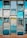 A series of glass panels arranged in a grid pattern, reflecting a scenic view of a serene landscape with greenery and a body of water. The panels are mounted using metallic bolts, creating a structured and geometric appearance. The view through the glass includes a clear blue sky with some clouds.