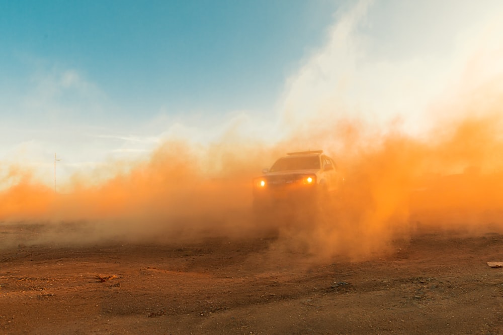 a truck driving down a dirt road in the desert