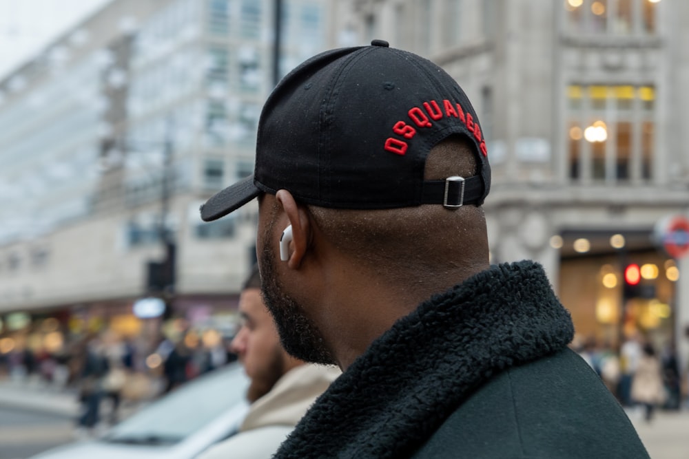 a man wearing a black hat with red lettering on it