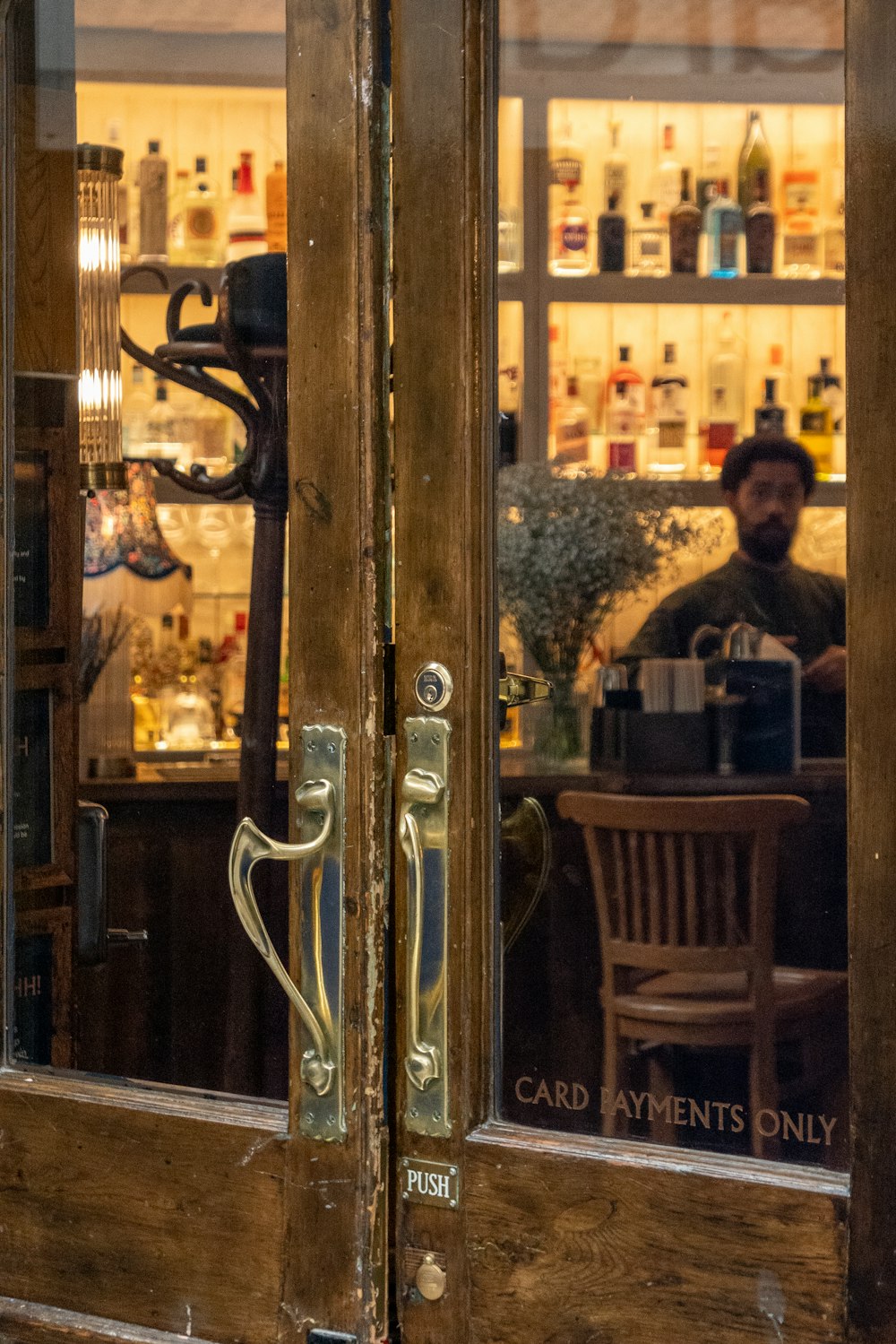 a man sitting at a bar behind a glass door