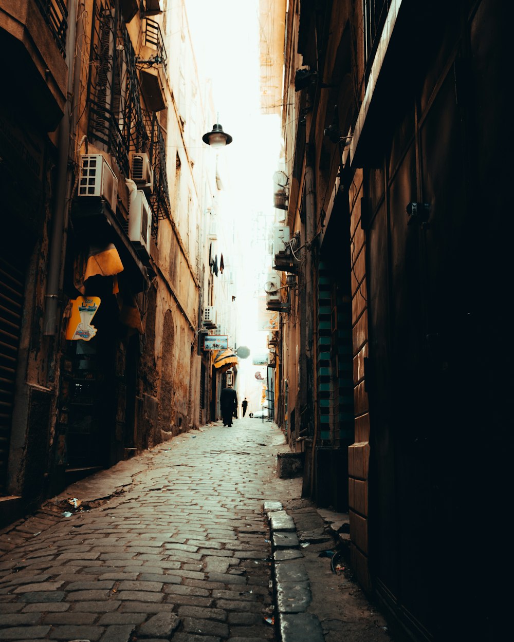 a narrow alleyway in a city with people walking down it