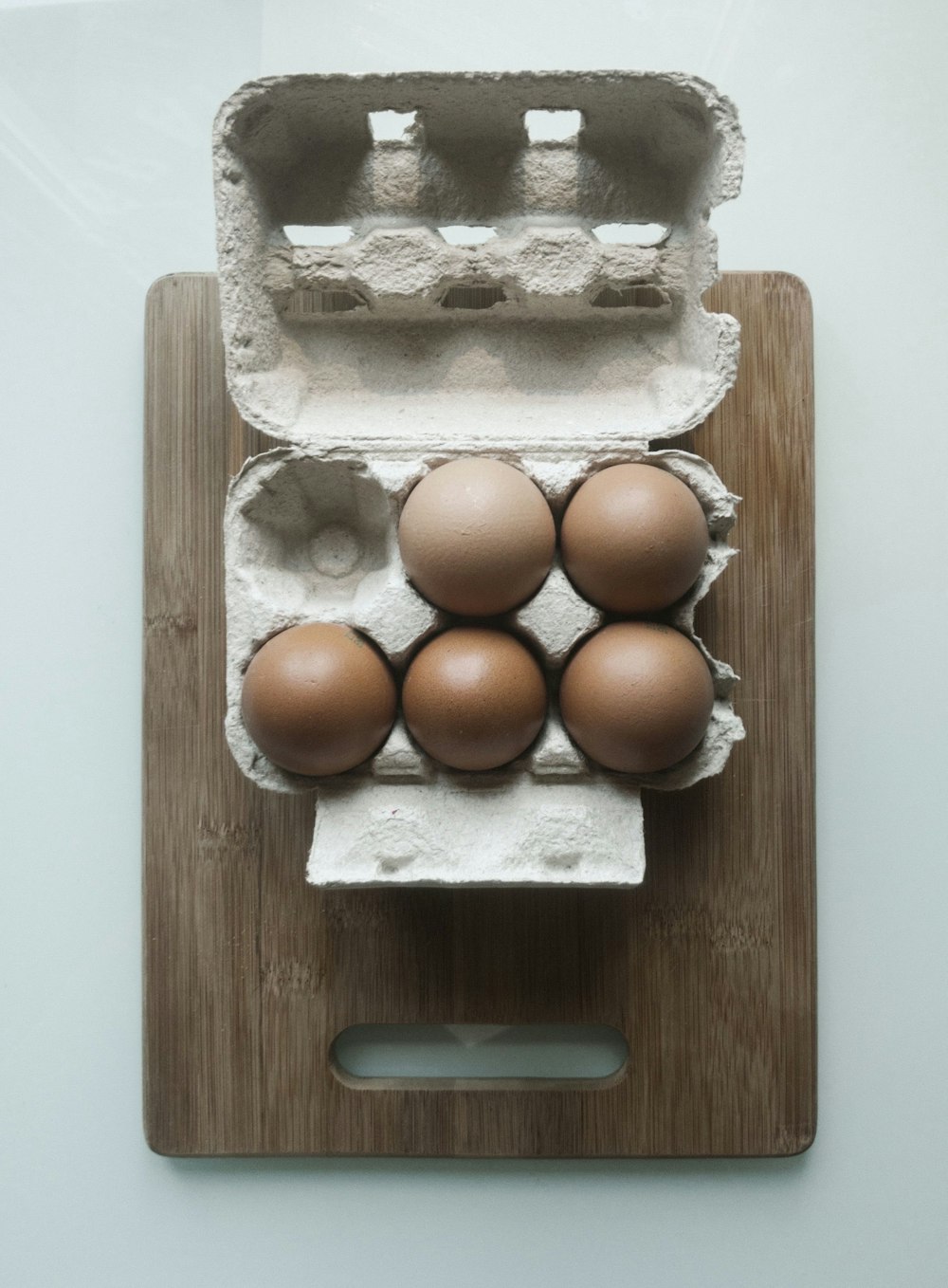 a carton of eggs sitting on top of a wooden cutting board