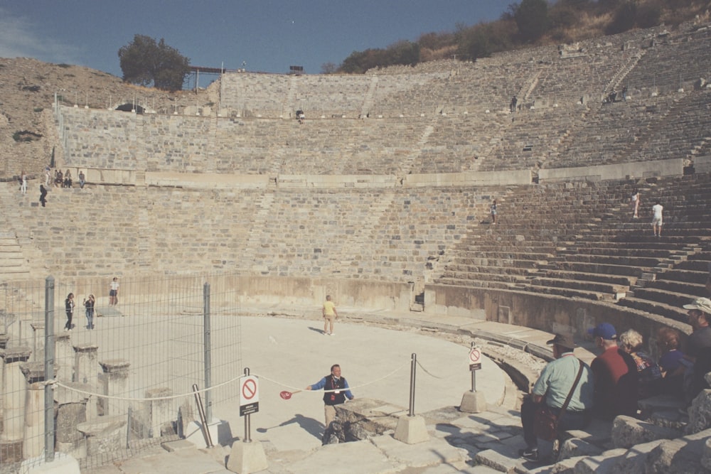 Un grupo de personas de pie alrededor de una arena de piedra