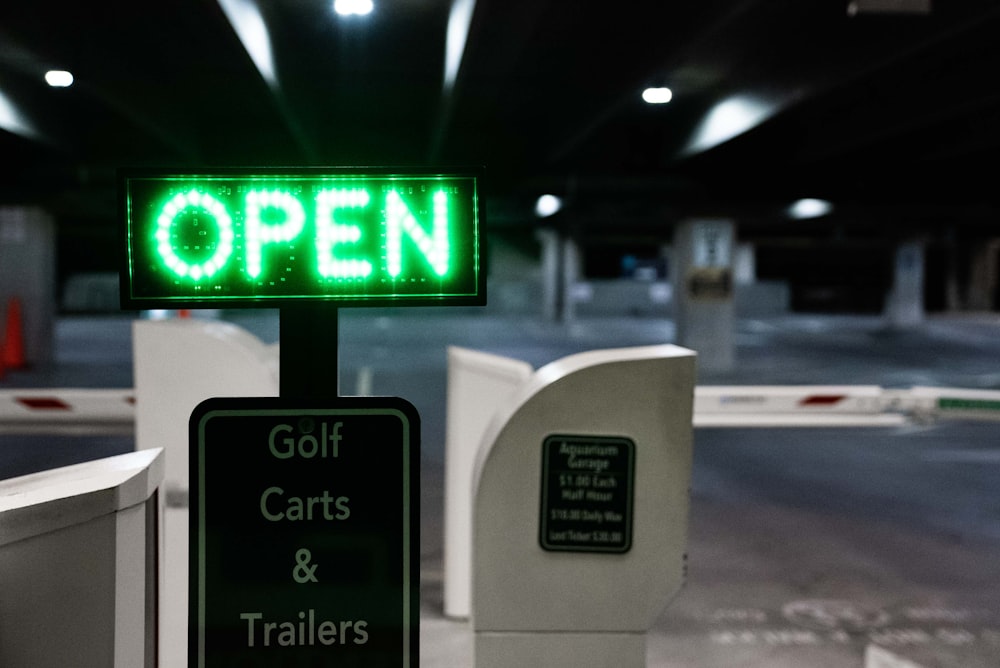 a green sign that says open and golf carts and trailers