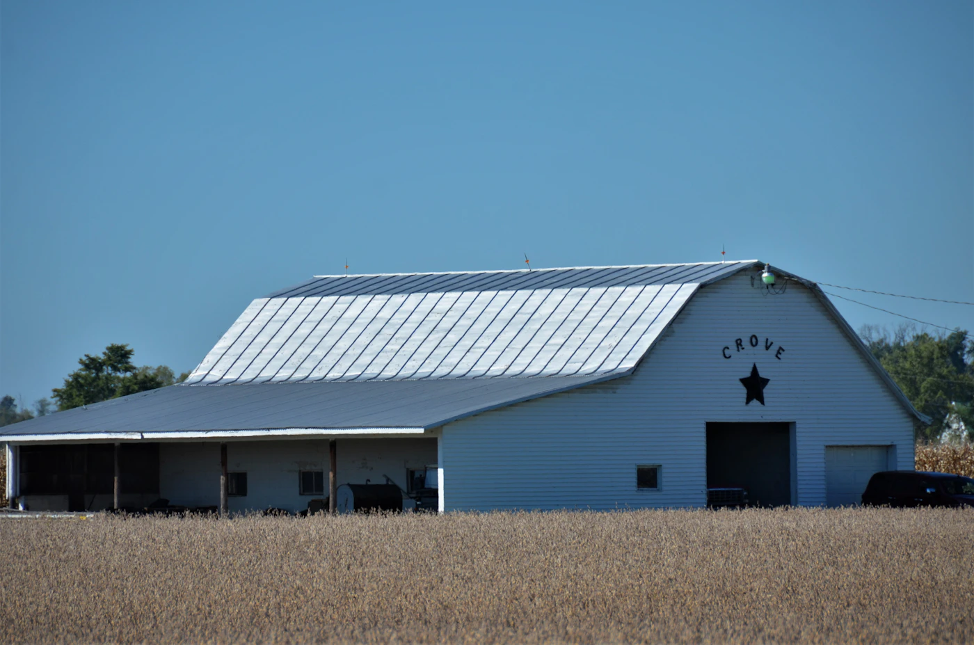 Large white pole barn building with metal roof on open land