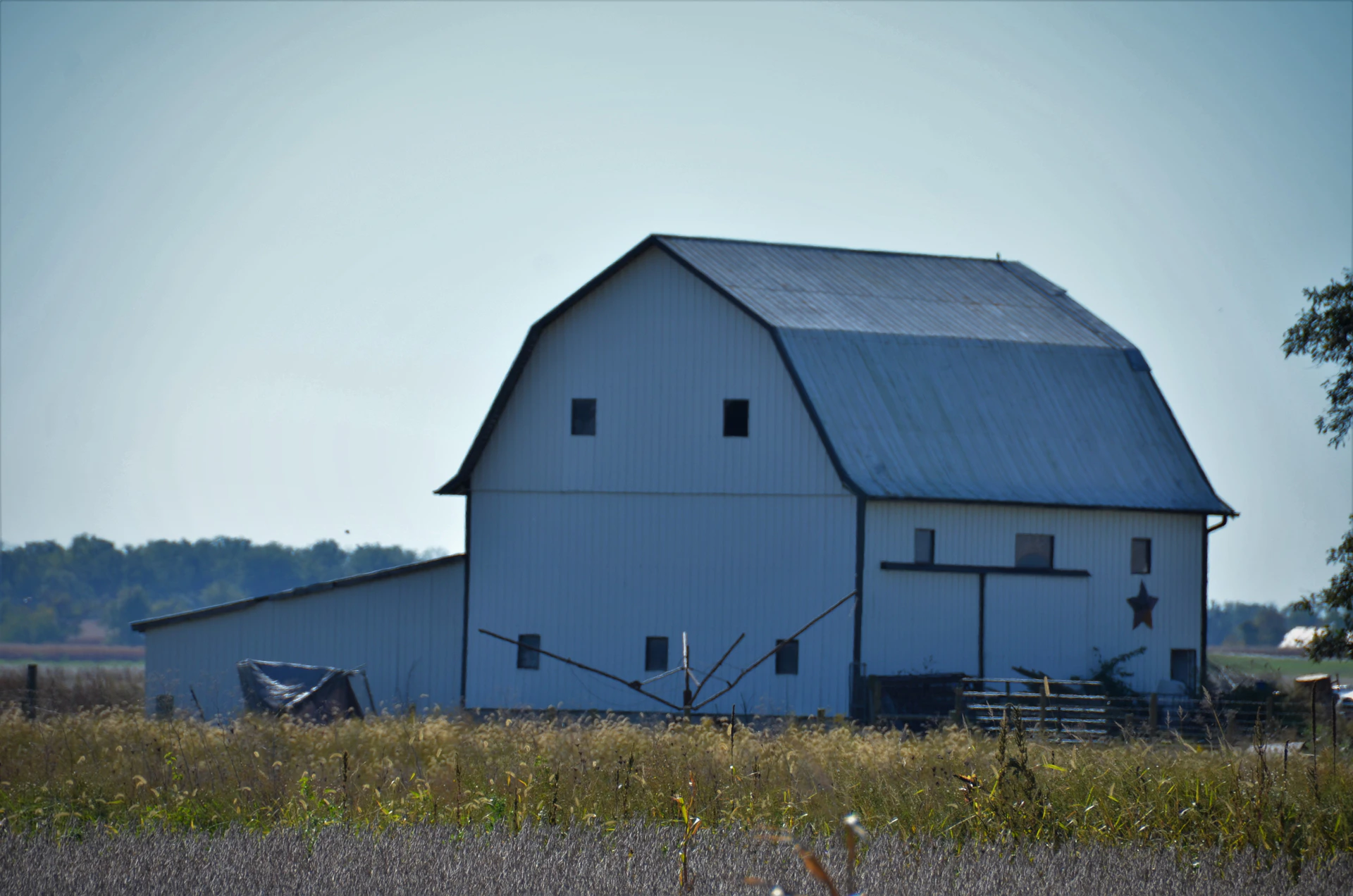 a large white barn sitting in the middle of a field