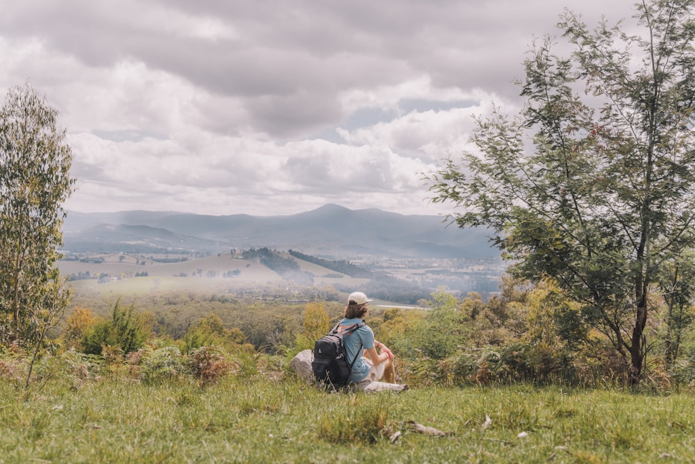 a person sitting on a hill with a backpack