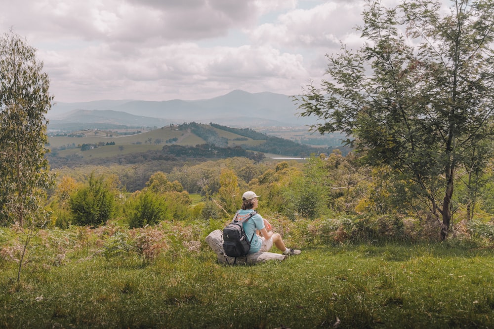 a person sitting on a rock in the middle of a field