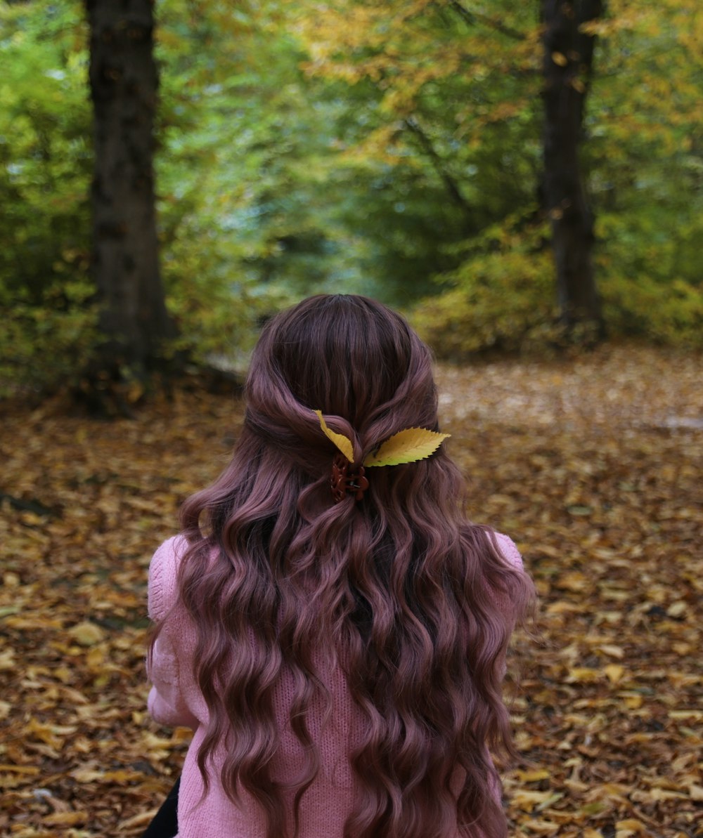 a young girl with long curly hair sitting in the leaves