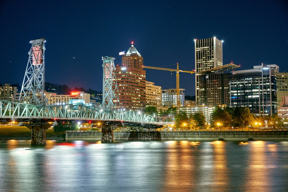 a city skyline at night with a bridge over the water