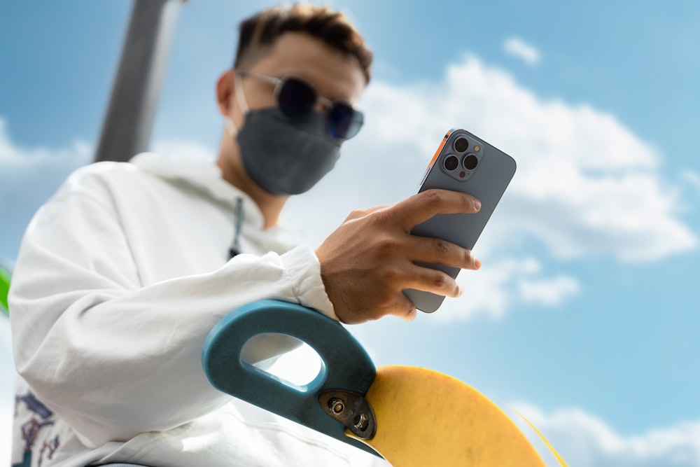 a man wearing a face mask while holding a cell phone