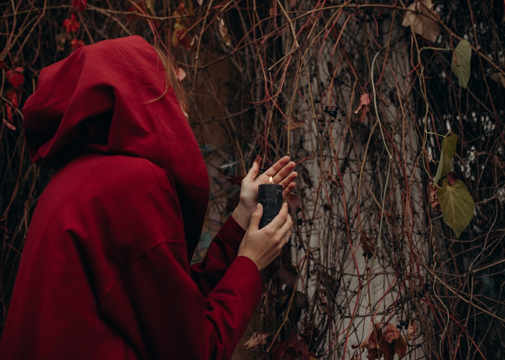 a woman in a red hoodie holding a black object