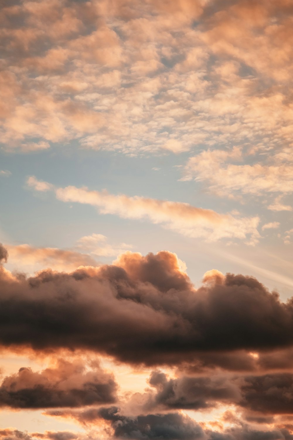 a plane flying through a cloudy sky at sunset